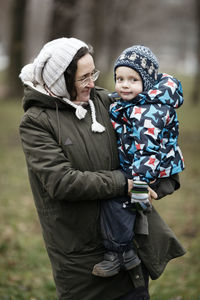 Grandmother and grandson standing outdoors during winter