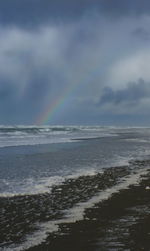 Scenic view of rainbow over sea against sky