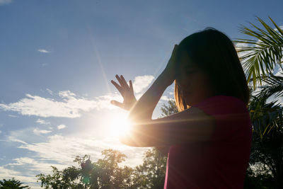 Low angle view of woman standing against bright sun