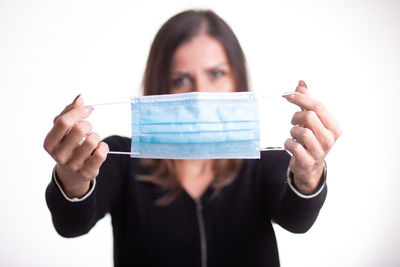 Portrait of young woman holding hands against white background