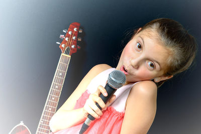 Portrait of girl singing against black background