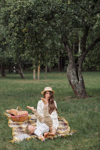 Woman sitting in basket on grass against trees