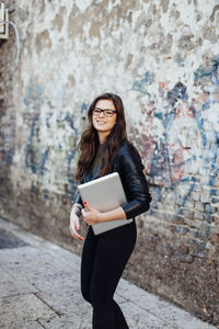 Young woman holding laptop outdoors