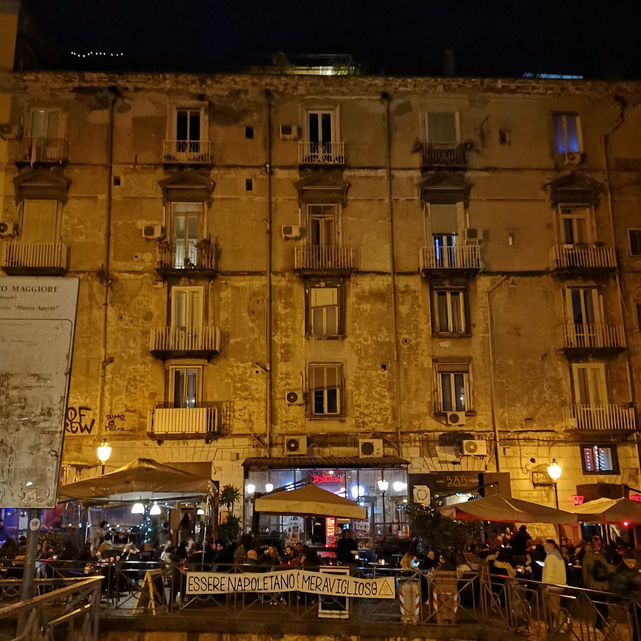PEOPLE ON STREET AGAINST ILLUMINATED BUILDINGS AT NIGHT