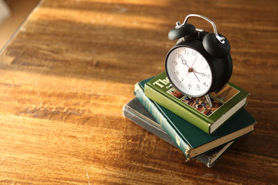 Alarm clock on top of books at table