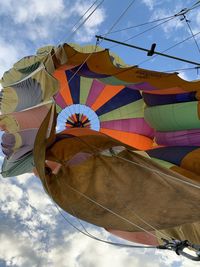 Low angle view of multi colored umbrellas hanging against sky