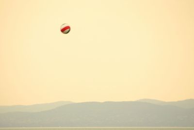 Balloons in mountains against sky during sunset