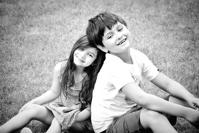 Portrait of smiling siblings sitting on field