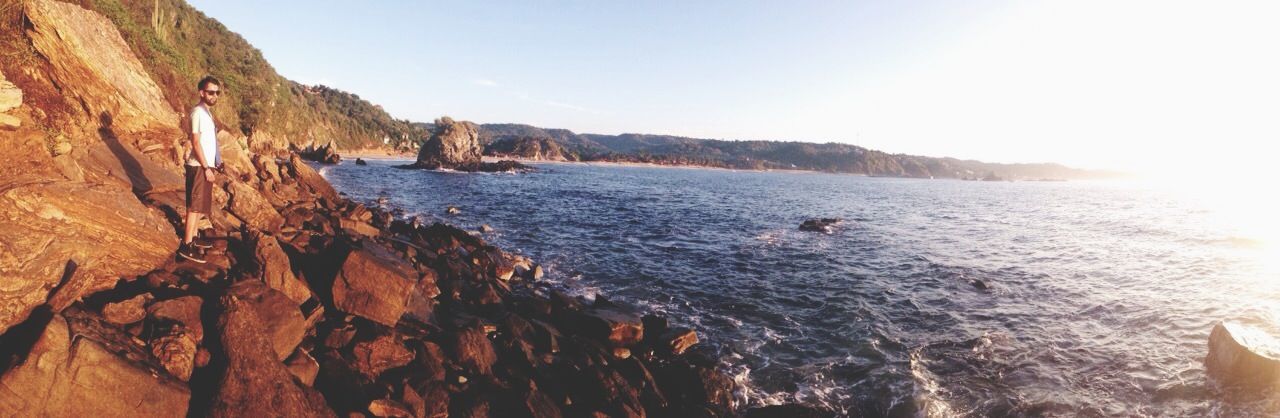 water, sea, scenics, sun, beauty in nature, tranquil scene, tranquility, sunlight, nature, rock - object, mountain, clear sky, rock formation, sunbeam, sky, idyllic, beach, lens flare, shore, cliff