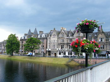 View of buildings by river against cloudy sky