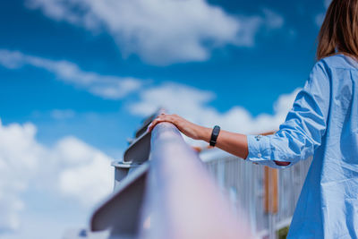 Low angle view of woman standing against blue sky