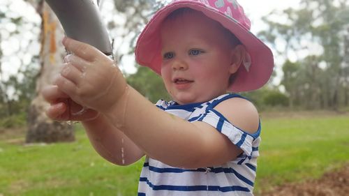 Toddler playing with water in pipe on field