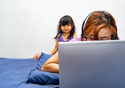 Young woman using mobile phone while sitting on bed