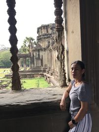 Low angle view of woman standing by ruins