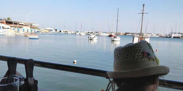 Sailboats moored at harbor against clear sky