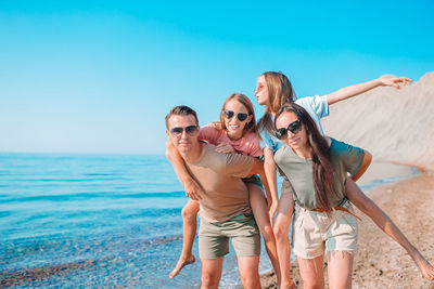 Portrait of people wearing sunglasses at sea shore against sky