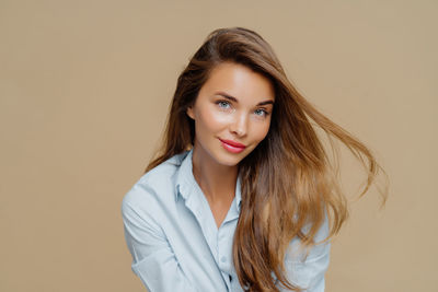 Portrait of young woman standing against pink background