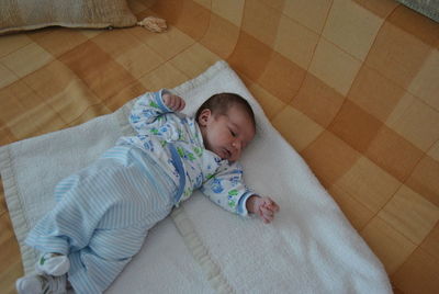 Close-up of cute baby lying on bed at home