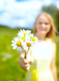 Close-up of woman holding white flowers on sunny day