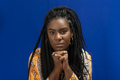 Portrait of young beautiful woman looking at camera with hands on chin.