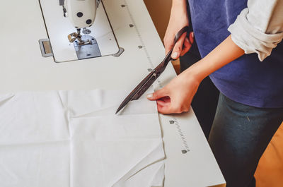 Dressmaker cuts white cloth with large knives