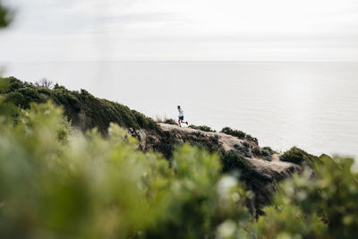 People standing on rock by sea against sky