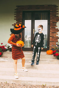 Brother and sister celebrate halloween on the street near the house in costumes and make-up