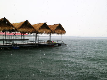 Stilt house on sea against clear sky