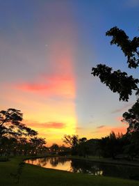 Silhouette trees by lake against sky during sunset