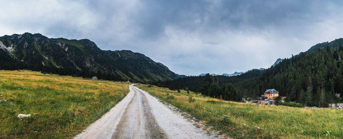 Panoramic view of road amidst field against sky