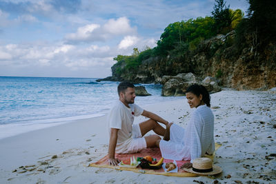 Side view of couple sitting on beach
