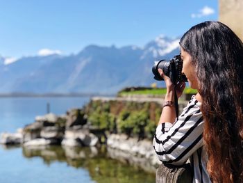 Woman photographing against mountain range