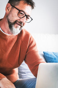 Man using laptop while sitting on sofa at home