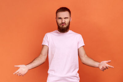 Portrait of young man standing against yellow background