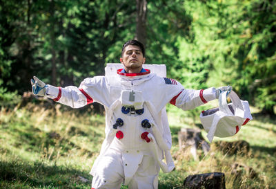 Astronaut looking away while standing in forest