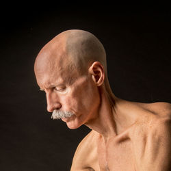 Close-up of mature man with mustache over black background