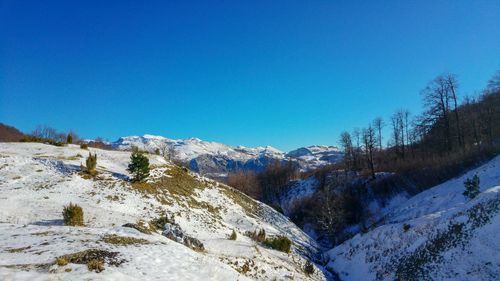 Scenic view of snowcapped mountains against clear blue sky