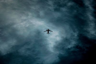 Low angle view of airplane flying against storm cloud