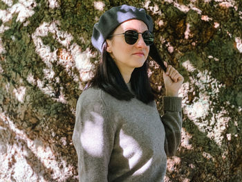 Portrait of young woman wearing sunglasses standing against plants
