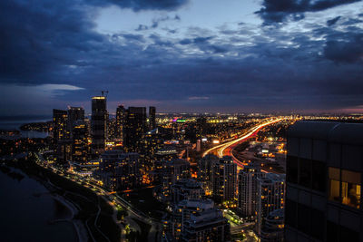 Illuminated cityscape against cloudy sky