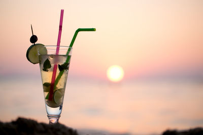 Cocktail by sea against sky during sunset