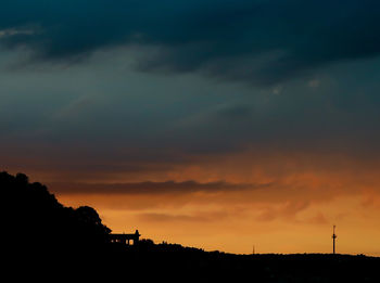 Silhouette landscape against dramatic sky during sunset