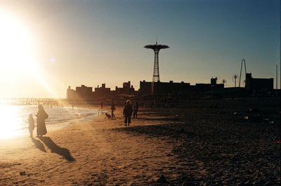 Silhouette people at coney island beach during sunset