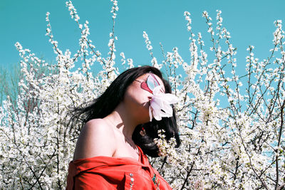 Young woman standing by flowering tree