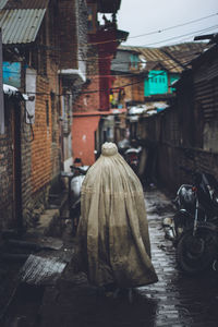 Rear view of people walking on street amidst buildings