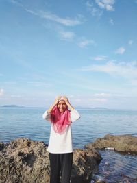 Portrait of woman standing on rock by sea against sky