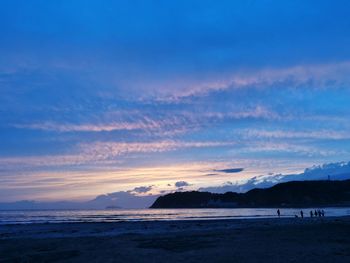 Scenic view of beach against sky at sunset