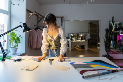 Young designer woman dressmaker work on new clothes collection in studio workshop. small business.