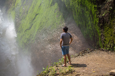 Man looking at view of waterfall standing against mountain