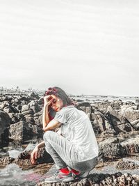 Young woman on rock against sky